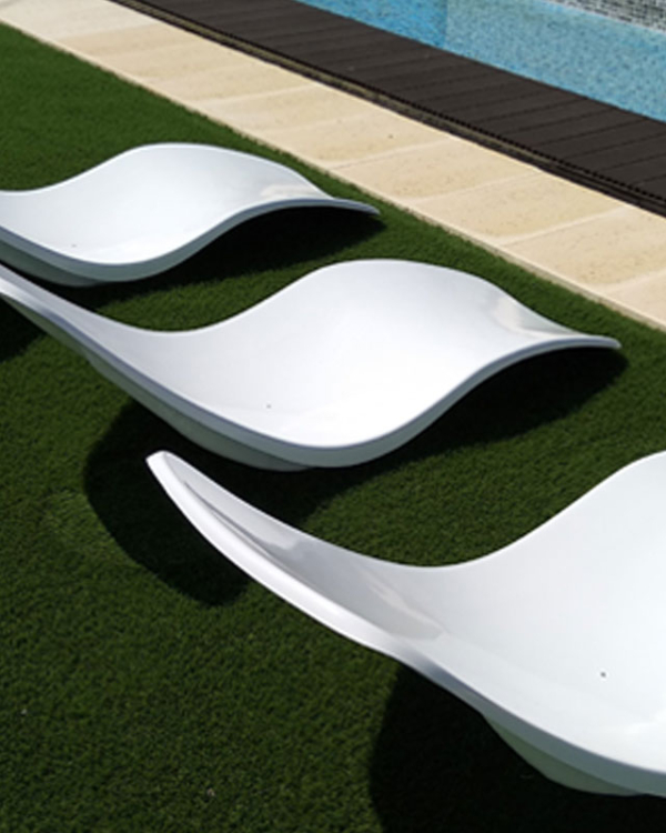 3 espreguiçadeiras fibra vidro junto a piscina num jardim com foco na lateral e curva